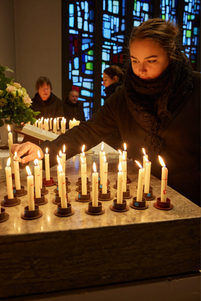 Chiara Christoph entzündet Erinnerungskerzen zur Vorbereitung einer Trauerfeier in einer Kirche