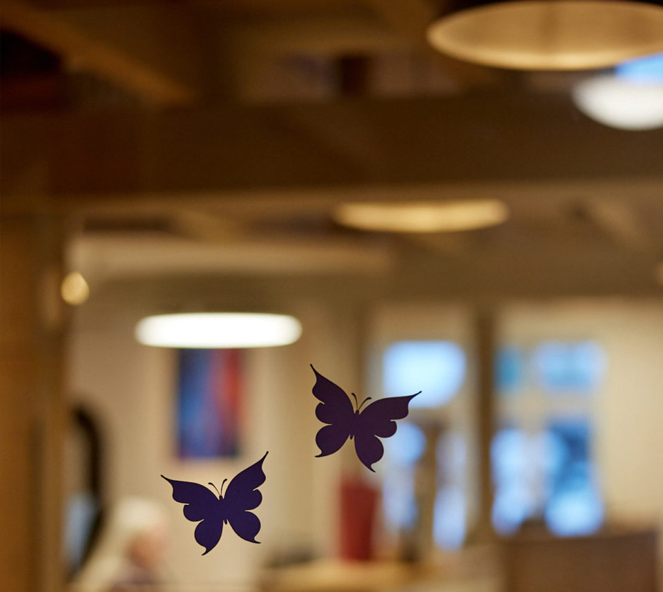 Blick durch die mit Schmetterlingen verzierte Glastür in das Büro des Bestattungshauses Schamborski